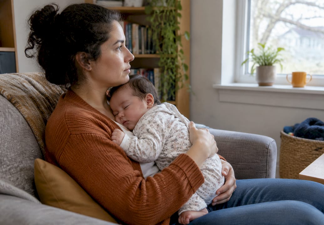 Mother awake while holding her sleeping infant
